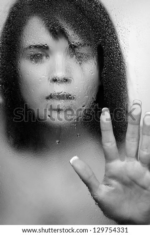 closeup beauty portrait of sexy woman from behind a wet window