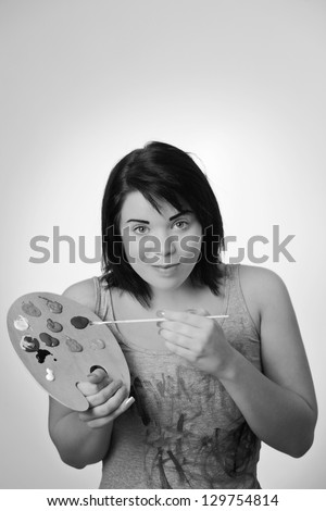 woman holding a artists painting palette and brush doing her make up