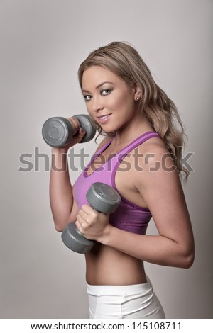 Woman in gym clothes holding dumbbells doing a work out