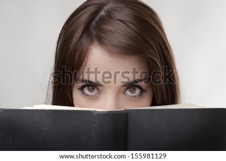just woman eyes peering over a hard back book
