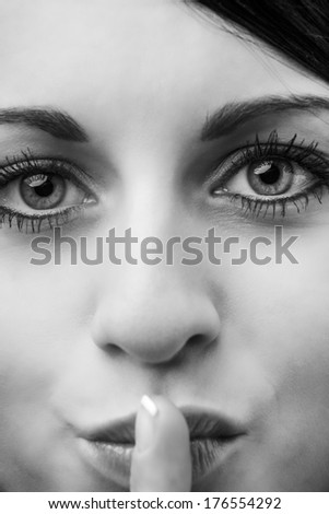 close up image of young woman with finger on her mouth to indicate that you should be quiet