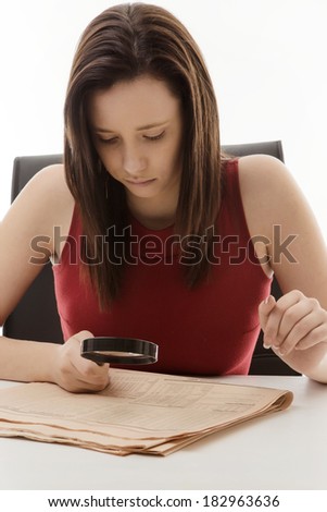 woman sitting down looking over the fine print with a magnifying glass