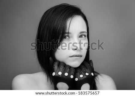 head shot of a young woman shot in the studio looking into camera model is wearing leather driving gloves