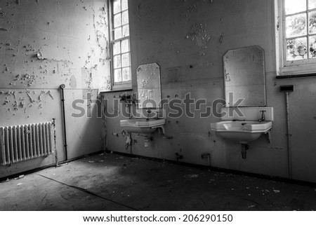 inside view of a deserted run down building showing broken bathroom sinks