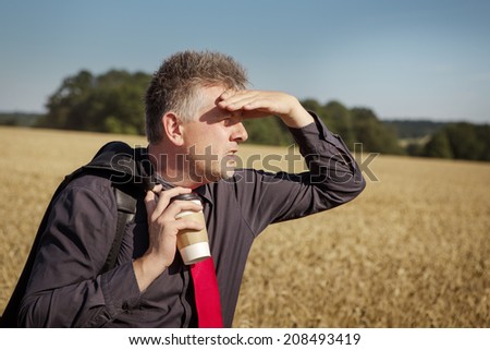 businessman standing in a field looking around