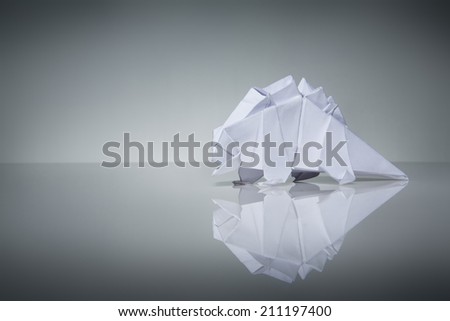 Still life image of a origami dinosaur make from plain paper