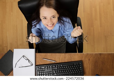 woman at her desk looking up very happy and excited, taken from a birds eye view