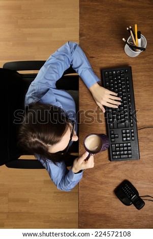 woman at her desk drinking a cup of tea, taken from a birds eye view