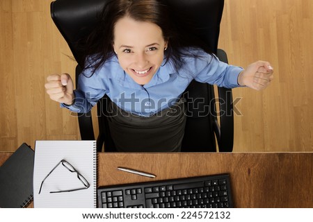 woman at her desk looking up very happy and excited, taken from a birds eye view