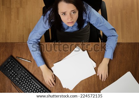 woman working at her desk not happy about her work load, taken from a birds eye view