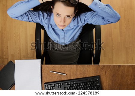 woman relaxing at her desk looking up at camera taken from a birds eye view