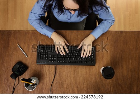 woman typing and working hard at her desk taken from a birds eye view