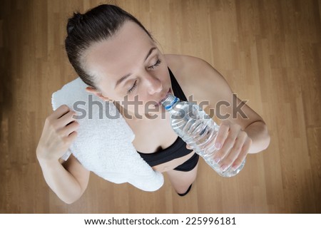 fitness woman drinking water after a workout, view point is high above the model