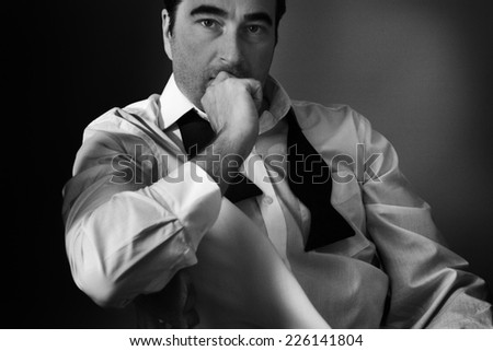 guy siting on a chair with a bow tie undone around his neck