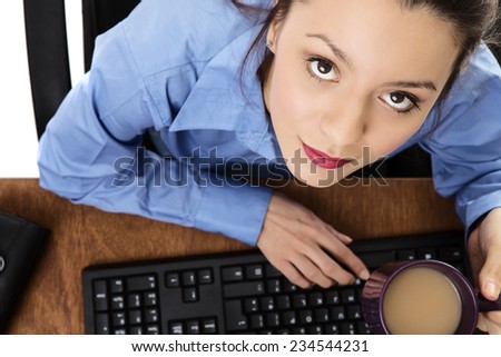 woman at hers desk drinking a cup of tea shot from a birds eye view looking down