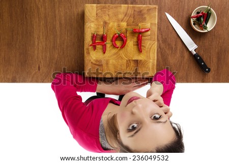 wooden chopping board with chillis making the word hot, taken from a birds eye view from above looking down at a woman