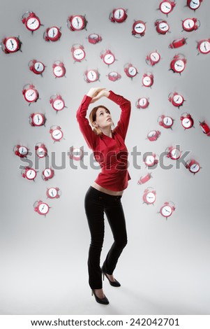 standing woman with arms up above her head protecting  her self from falling clocks