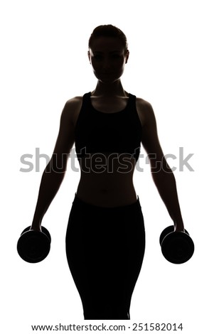 silhouette of a young woman working out lifting dumbbells