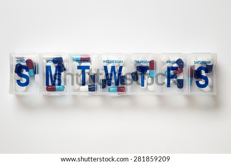 still life image of a plastic weekly pill box with pills inside the box