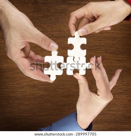 group of adult hands male and female holding jigsaw pieces shot from above looking down