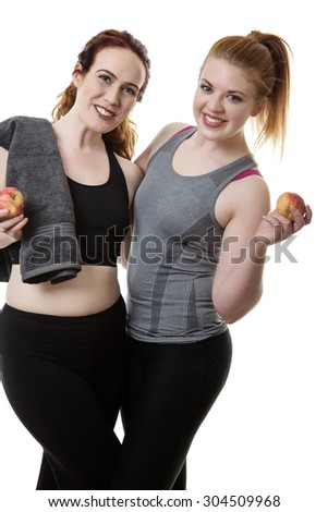two happy friends eating an apple together after a work out