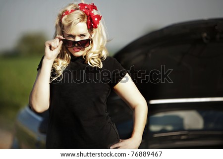 young sexy woman standing by a car which has broken down with it\'s  bonnet up