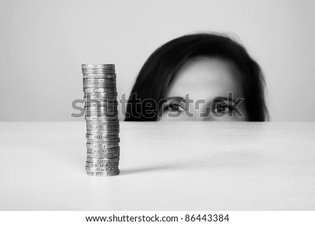 young woman looking at money on a white desk (English money)