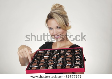 woman holding a large box of chocolates thinking what one to eat next