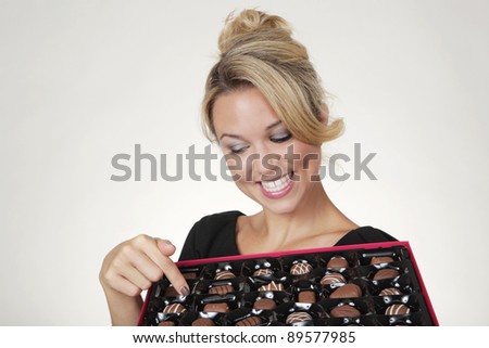 woman holding a large box of chocolates thinking what one to eat next
