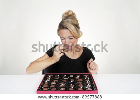 woman with a large box of chocolate and she just eaten one she does not like