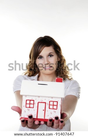 woman holding out in her arms a model house money box to save up for her dream house