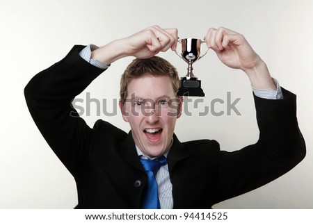 businessman holding up a cup medal to show that hes a winner