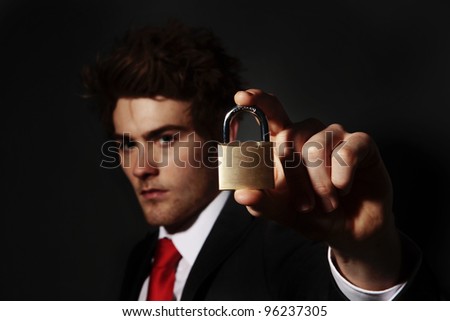 low key portrait image of businessman holding up a pad lock
