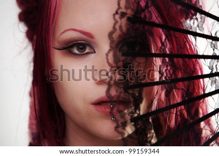 woman with dread lock hair holding a fan up to her face