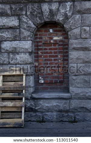 Unique shaped bricked window on rustic rock wall