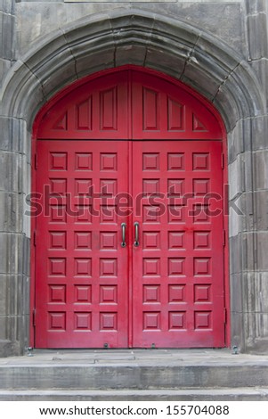 Two detailed red doors surrounded by vintage block archway.