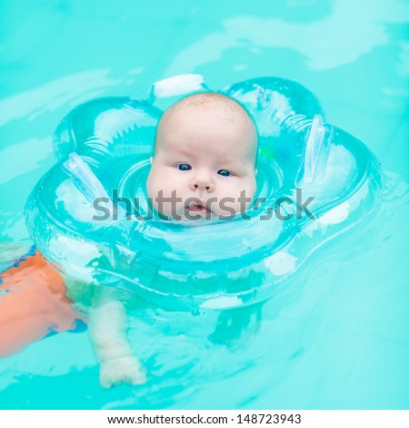 Baby swimming with neck swim ring in pool