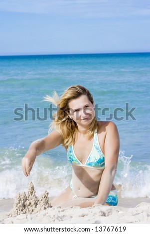 Young woman making sandcastle on the tropical beach