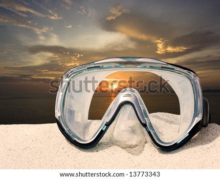 Diving equipment mask on white sand beach on sunset time.