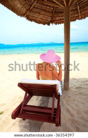 Young woman sunbathing on the chair near the ocean