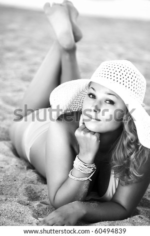 Young woman sunbathing on the beach. High key image