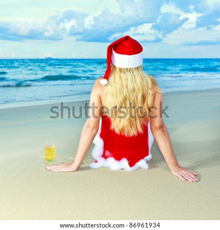 Miss Santa sitting near the ocean with glass of wine
