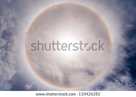 Sun with circular rainbow sun halo in sky with cloud
