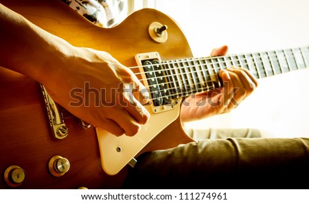 man playing electric guitar with nature light