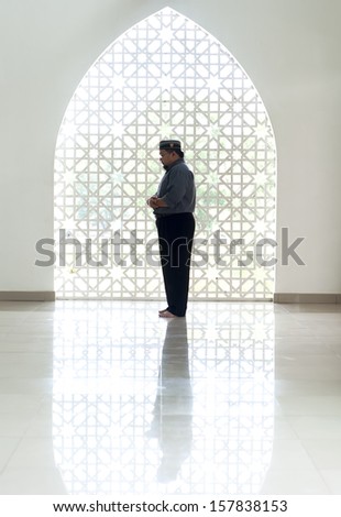 A highkey image of a Muslim prays