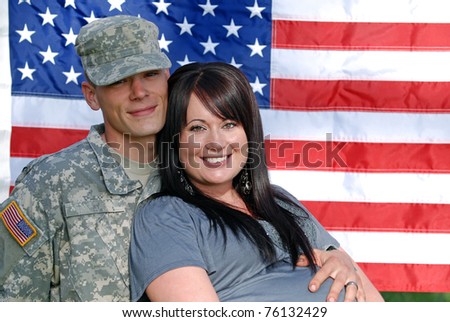 Young couple in front of the United States flag. Young man is in the military.
