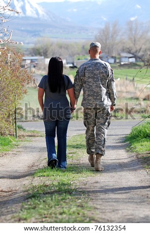 Young military couple walking down a country lane holding hands.