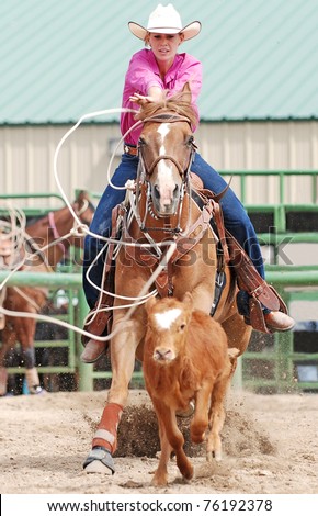 Young woman on a horse roping a calf in a rodeo competition. Motion blur with calf and rope.