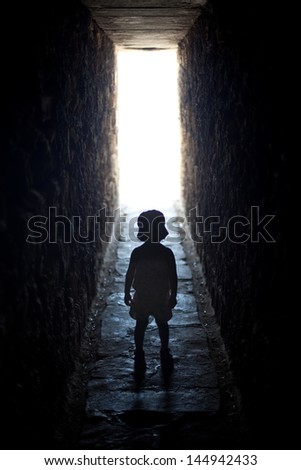 Silhouette of a small girl in a dark tunnel