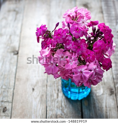 Pink flowers in vase on wooden background